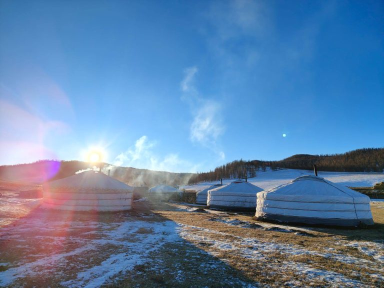 White Mongolian yurts on the snowy steppe at sunrise – shamanic journey to Mongolia