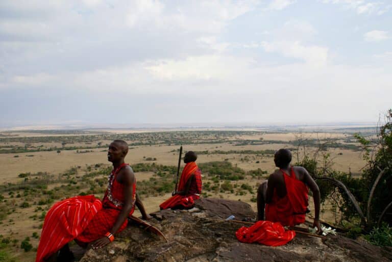 Three Maasai men in red shukas overlooking the Kenyan savannah
