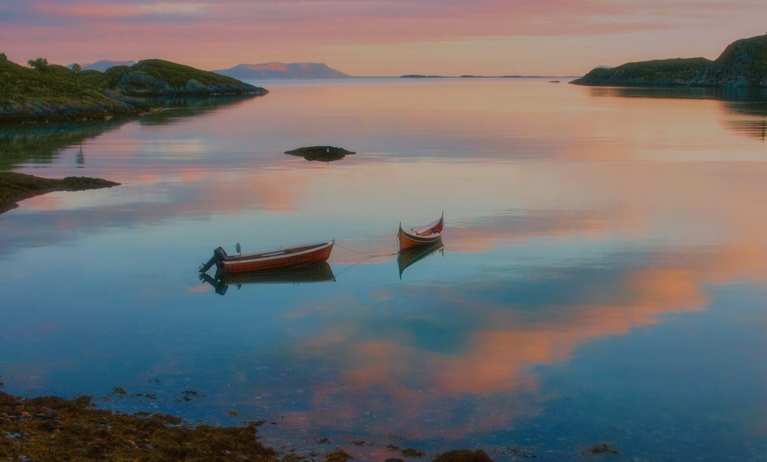 Boats on a calm fjord under the midnight sun